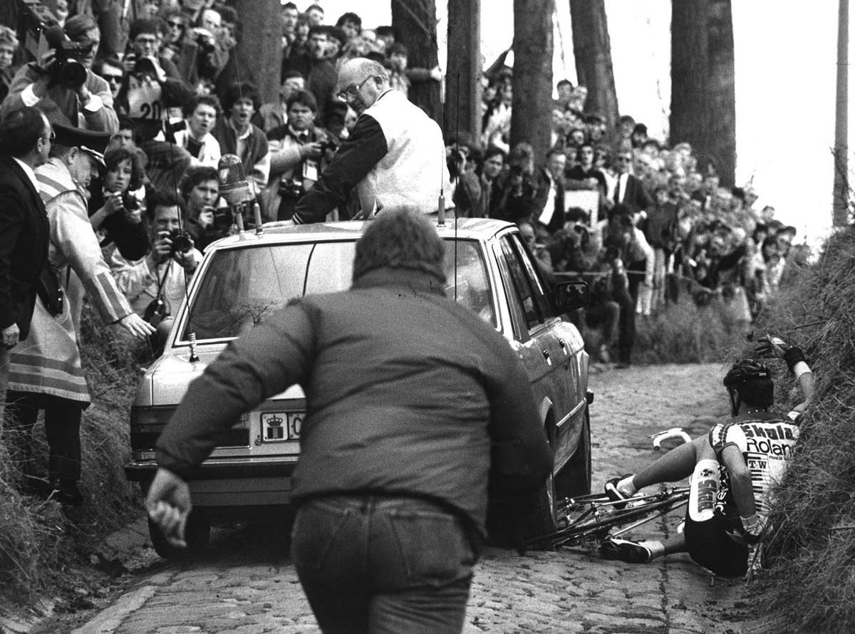 Keine Zeit zu warten, das Feld kommt - der Begleitwagen fährt über das Rad von Jesper Skibby am Koppenberg 1987